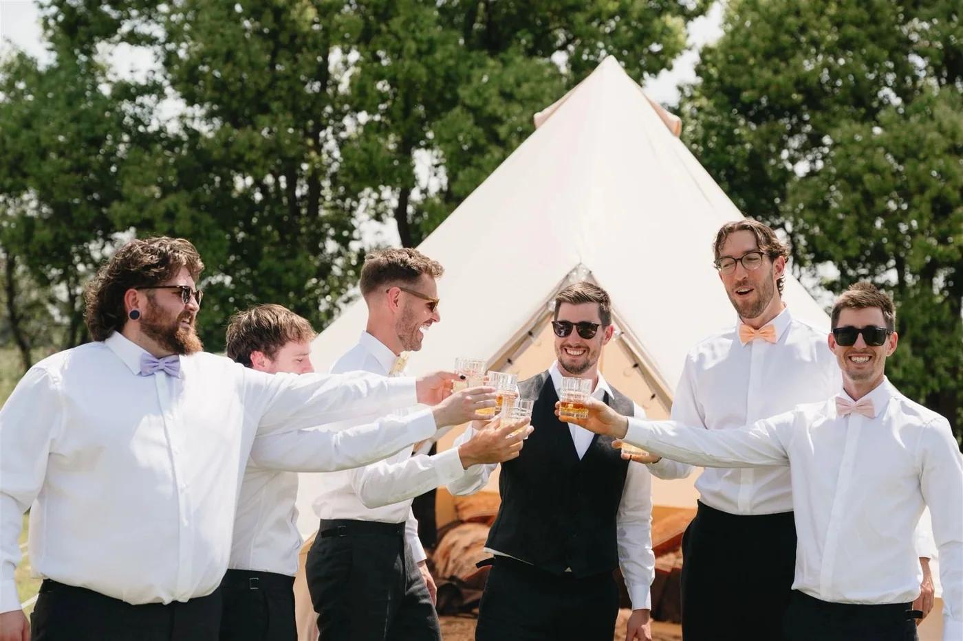 Groomsmen toasting outside a bell tent