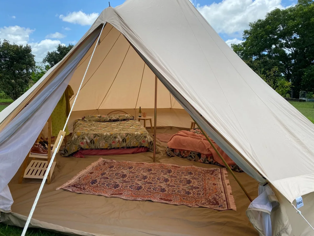 Cosy Bell tent interior with double height bed, rugs and lanterns